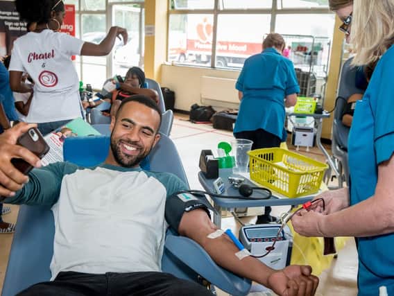 A male patient takes a selfie to let people know he is happy to give blood. Photo by Ian Enness.