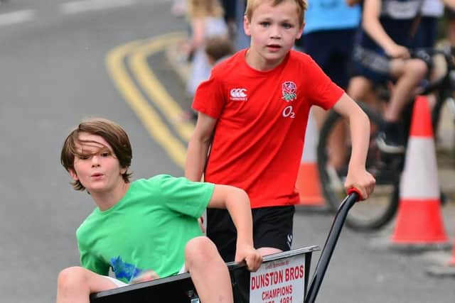 Matthew Pawson, grandson of Arnold Pawson, pictured pushing Harry Wellings to victory in the Junior Race.  Picture: Marie Caley NDFP-04-07-19-BraithwellWheelbarrow-2