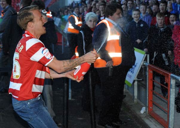 Doncaster Rovers James Coppinger sprays champange into the crowd as they celebrate the presentation of the nPower League One Trophy. Picture: Andrew Roe