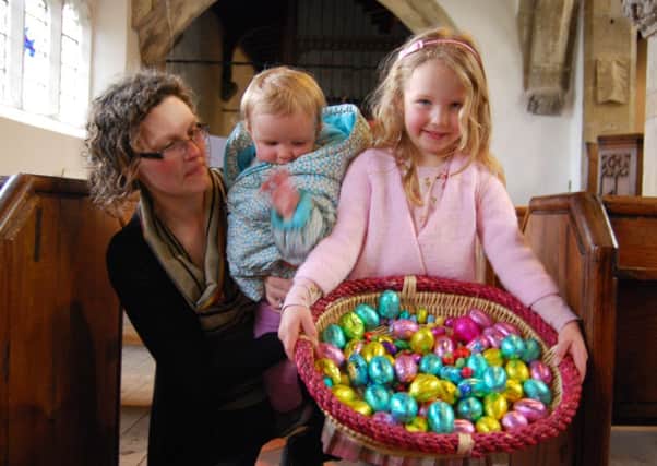 An Easter-themed coffee morning with hot cross buns and a childrens Easter egg hunt in All Saints Church raised £230 for Church funds. Pictured is Rachel Bowes with children Erin (centre) and Emily and some of the Easter eggs to be won.