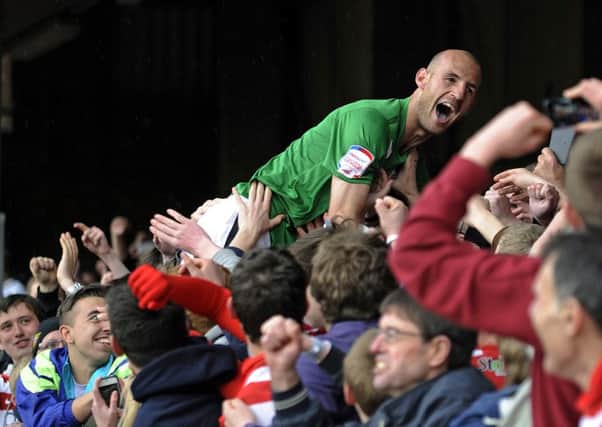 Rob Jones is mobbed by Rovers supporters after clinching the League One title at Brentford in 2013.