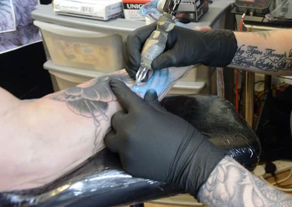 A tattooist  at work on one of his customers.