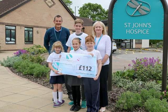 Donating the funds raised from their cake sale are Alice Coen (front left), Lydia Eastwood (front centre), Joseph Coen (front right) and Evan Restell (back centre) with Chris Smith (back left) and Lindsey Richards (back right) from the hospice.
