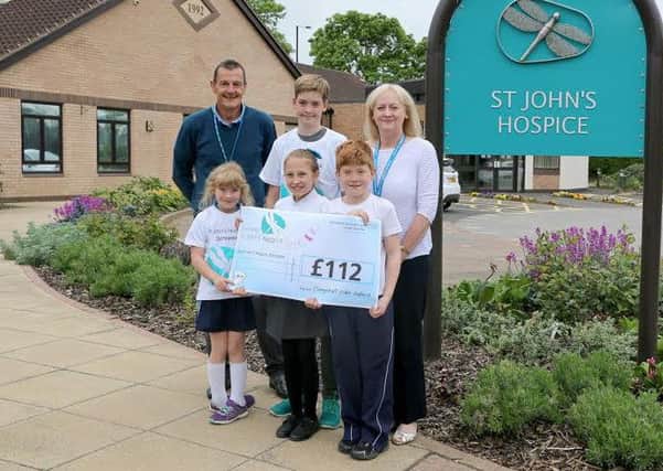 Donating the funds raised from their cake sale are Alice Coen (front left), Lydia Eastwood (front centre), Joseph Coen (front right) and Evan Restell (back centre) with Chris Smith (back left) and Lindsey Richards (back right) from the hospice.