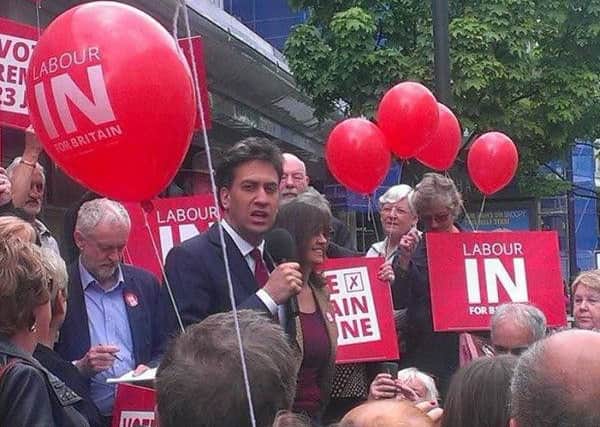 Jeremy Corbyn jots down notes for his speech while Ed Miliband addresses the rally.