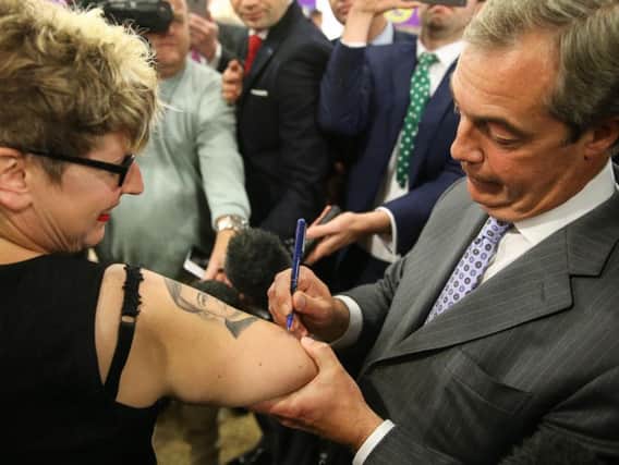 Nigel Farage signs the arm of fan Kerry Webb, who has a tattoo of the politician on her arm at last year's UKIP conference in Doncaster.