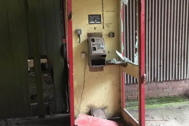 A telephone kiosk lies broken and abandoned.