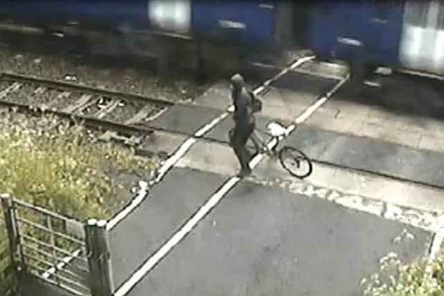 The cyclist narrowly avoids being hit by a train.