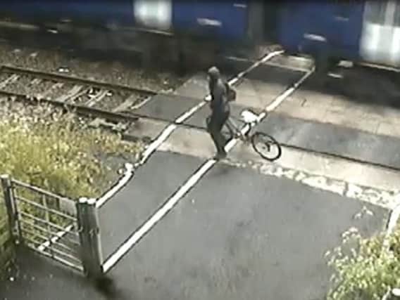 The cyclist narrowly avoids being hit by a train.