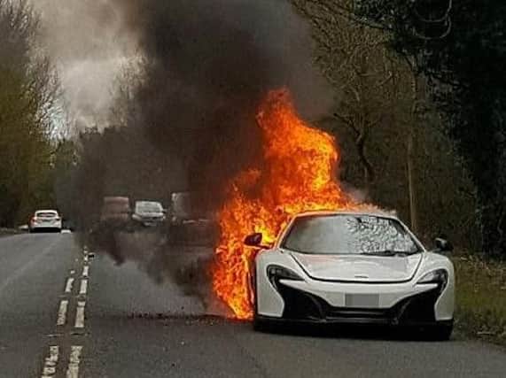 The McLaren ablaze at the side of the road. (Photo: SWNS).