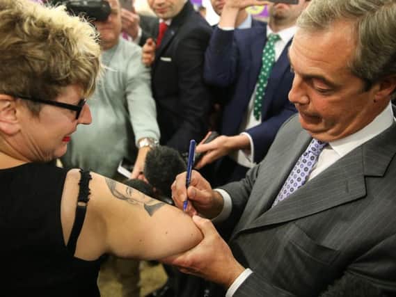 Former UKIP leader Nigel Farage signs an autograph for a fan with a tattoo of the politician in Doncaster in 2015.