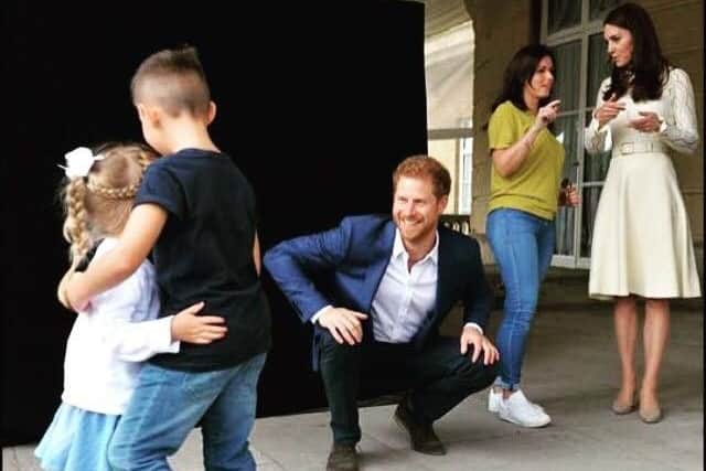 Prince Harry entertains Jayden and Amelia while their mum Samantha chats with the Duchess of Cambridge in the background
