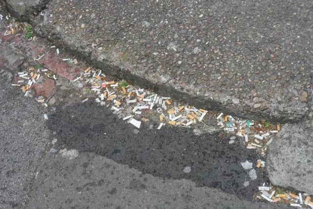 A pile of discarded cigarette ends in the gutter.