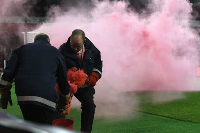Stewards clear a flare thrown onto the pitch