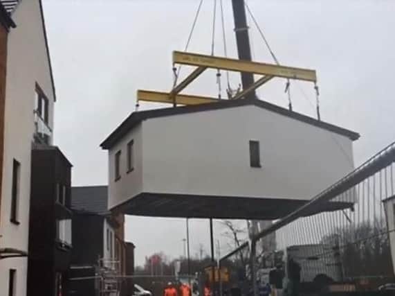 A huge crane lifts the upper floor of a new modular home into place on Woodfield Way