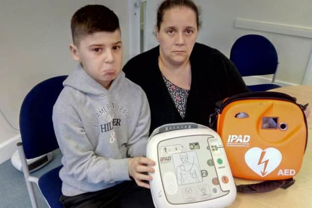 Dan Fagg and mum Hayley Thomson with the damaged defibrillator, which was reported stolen