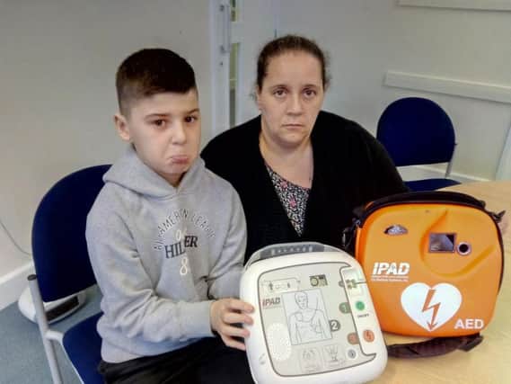 Dan Fagg and mum Hayley Thomson with the damaged defibrillator, which was reported stolen